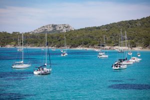 dove alloggiare a porquerolles? Barche ormeggiate su una delle spiagge di Porquerolles con acque turchesi.
